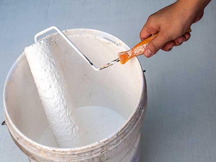 dipping paint roller into paint